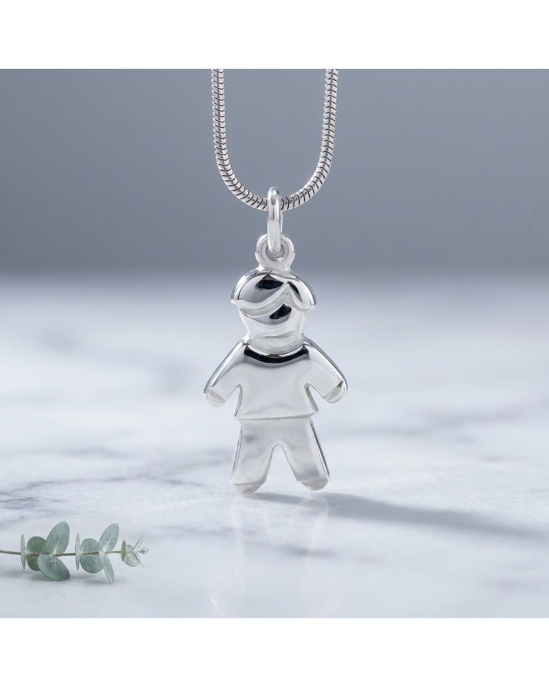 Pendentif en argent en forme de petit garçon stylisé suspendu à une chaînette chainette argentée, posé sur une surface claire. P