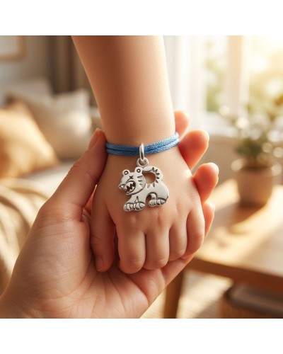 Bracelet BB TIGRE sur le poignet d’un enfant, cordon bleu avec un pendentif tigre argenté.