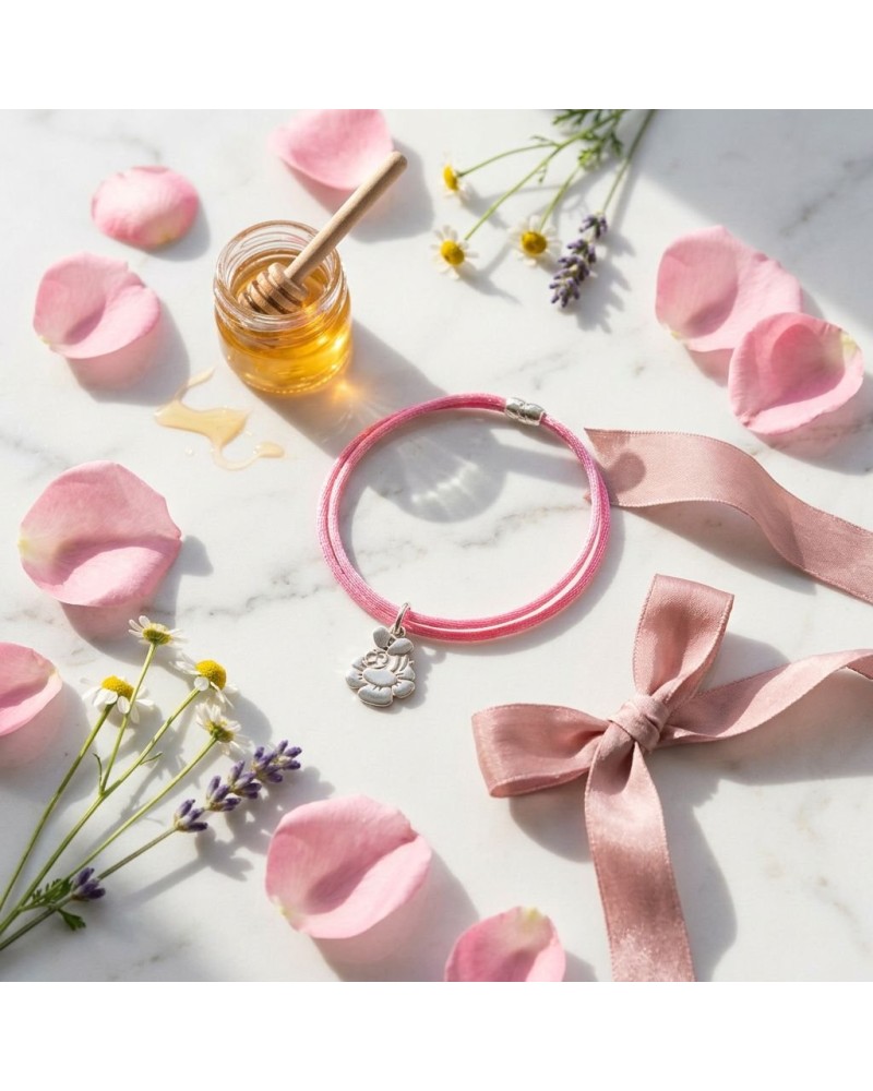 Bracelet BB ABEILLE rose en cordon, avec pendentif coccinelle sur fond floral pastel et ruban rose clair à côté.