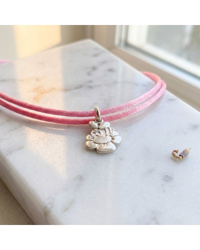 Bracelet BB ABEILLE avec cordon rose et pendentif abeille en métal argenté sur une surface en marbre.