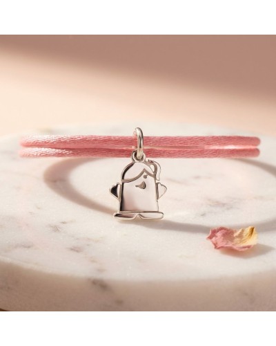 Bracelet élastique rose avec pendentif charm fantôme argenté représentant une petite fille, sur une surface marble claire.