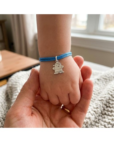 Petit poignet d’enfant avec bracelet bleu en corde et médaillon argenté en forme de mini personnage porte-clé. Produit: Bracelet