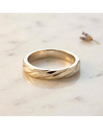 Alliance ENTRELACE Femme en or: bague minimaliste dorée avec motifs torsadés sur fond clair.