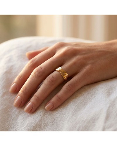 Alliance TRESSE Femme en or: doigt portant une bague dorée moderne à motif torsadé sur fond neutre.