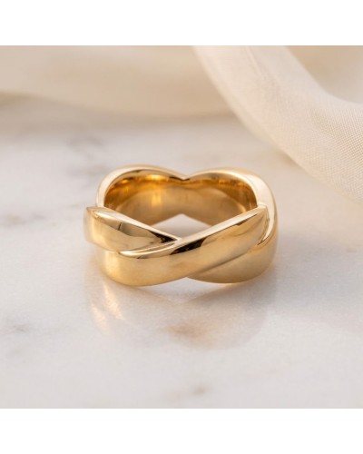 Alliance TRESSE Femme en or: bague en or doré en forme de nœud torsadé, posé sur une surface claire.