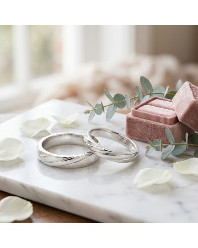 Alliance ENTRELACE Femme en or: deux bagues argentées sur marbre avec bouquet de eucalyptus et pétales, boîte rose velours.