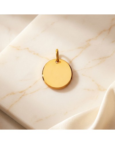 Médaille ronde en or jaune 18k, pendentif lisse avec anneau de suspension, posé sur marbre.