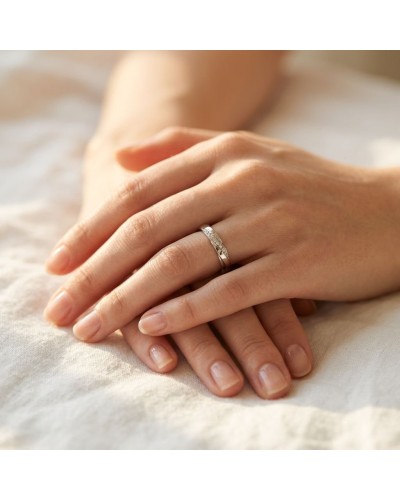 Alliance demi-empierrée en or portée sur le doigt d’une main féminine, posé sur une surface claire.