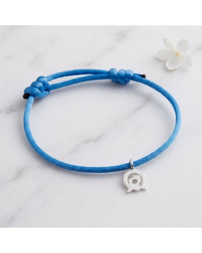 Bracelet bleu en cordon avec petit pendentif argenté en forme d’élément central, posé sur marbre. Bracelet CONNEXION Murial sout