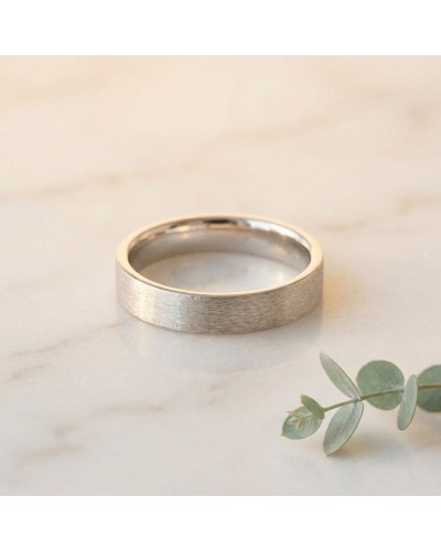 Alliance effet brossé pour homme en or: alliance masculine en or brossé sur pierre, avec brin de eucalyptus au côté.