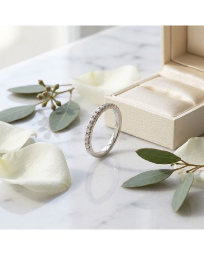 Alliance MODESTE demi-empierrée en or blanc argenté avec diamants, présentée près d’une box satinée et fleurs blanches.