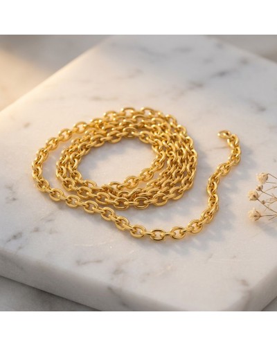 Chaîne forçat ronde en or jaune 18k, 1,3 mm, 40 cm, présentée en spirale sur marbre avec éclat métallique.