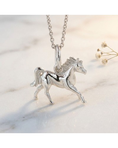 Pendentif en argent LITTLE PACHA: cheval miniature sculpté, chaîne argentée, posé sur surface claire.