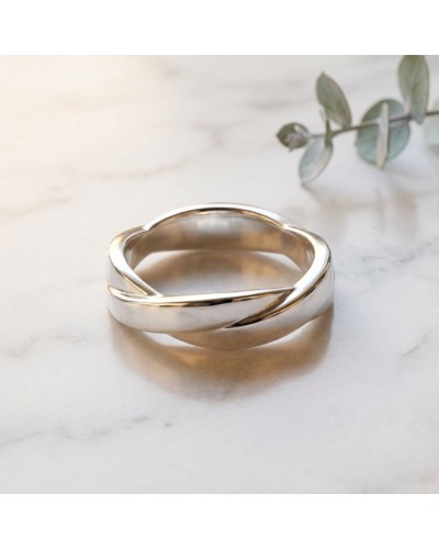 Alliance TRESSE Homme en or: bague moderne en argent avec motif torsadé, posé sur marbre, feuille d’eucalyptus en arrière-plan.