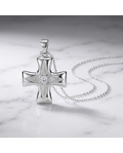 Pendentif croix NEW-AGE en argent avec pierre centrale scintillante, sur une chaîne fine, posé sur marbre.