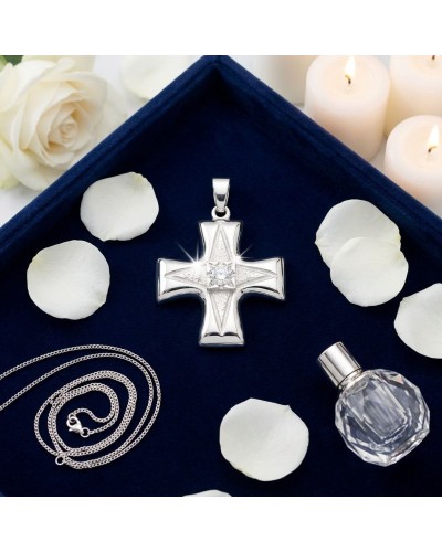 Pendentif croix NEW-AGE en argent brillant au centre, entouré de pétales blancs et bougies sur fond bleu.