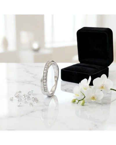 Alliance croisée en or blanc avec diamants sertis, accompagnée d’un boîtier noir et de perles orchids sur marbre.