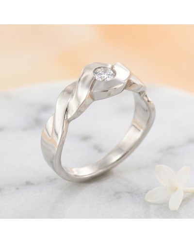 Alliance SOL TRESSE 1 diamant Femme en or : bague en or argenté à motif torsadé avec diamant central sur fond marble.