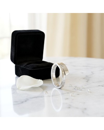 Alliance TOI + MOI: bague moderne en or argenté avec pierre scintillante, présentée près d’un coffret noir.