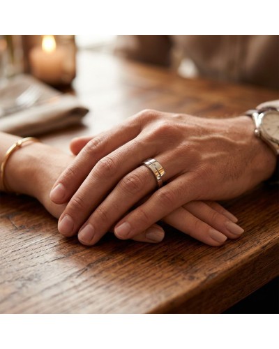 Alliance TOI + MOI : doigt masculin portant une bague argentée avec diamant, posé sur une table en bois.