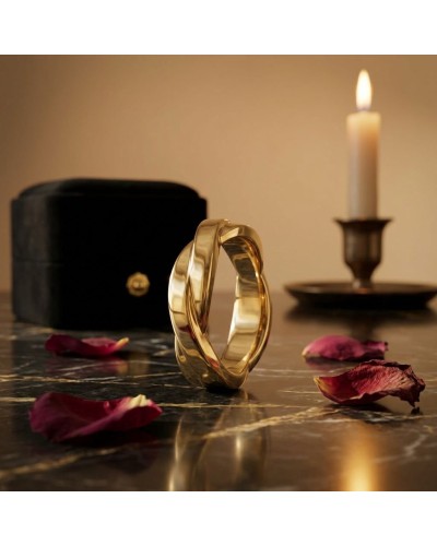 Alliance TRESSE Homme en or : bague masculine dorée en spiralé, posée sur marbre avec bougie et boîte noire en arrière-plan.