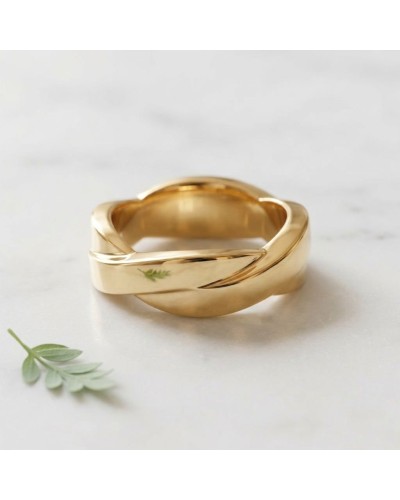 Alliance TRESSE Homme en or, bague dorée avec motif torsadé, posée sur surface blanche avec une petite feuille verte en premier