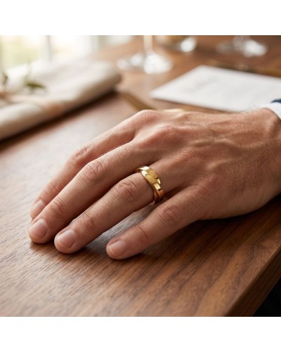 Alliance TRESSE Homme en or : doigt masculin portant une large bague dorée sur une table en bois.