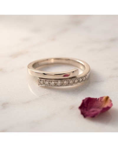Alliance TOI + MOI en or avec ligne de diamants sur bijoux féminin, posé sur marble, pétale rose à côté.