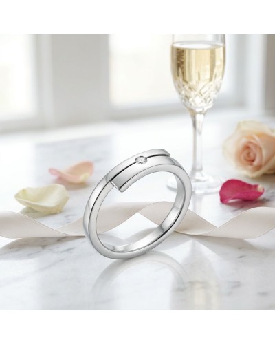 Alliage TOI + MOI 1 diamant: bague en or argenté avec un petit diamant, présentée sur marbre avec coupe de champagne et rose pas