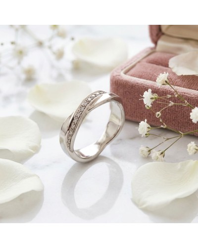 Alliance TRESSE demi-empierrée en or pour femme avec diamants, présentée près d’un boîtier rose et de pétales blancs.