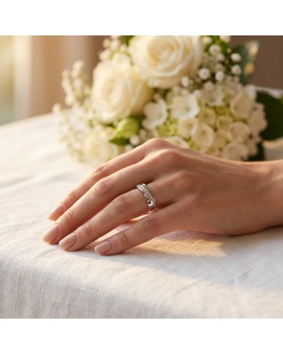 Alliance demi-empierrée en or sur doigt féminim, avec bouquet de mariage en arrière-plan.