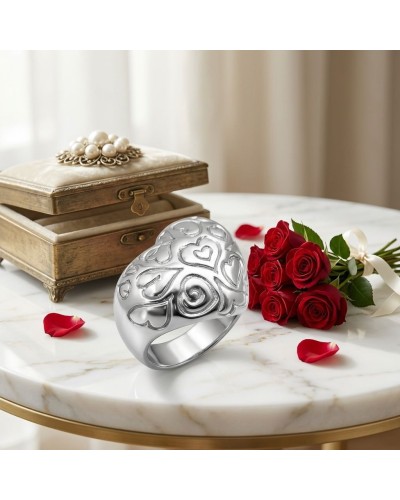 Anneau argenté sculpté de cœurs, posé sur une table en marbre avec bouquet de roses rouges et vieille boîte; produit Bague Atout