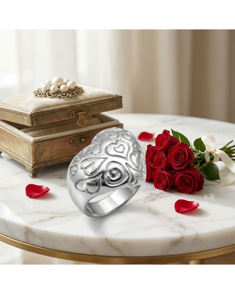 Anneau argenté sculpté de cœurs, posé sur une table en marbre avec bouquet de roses rouges et vieille boîte; produit Bague Atout