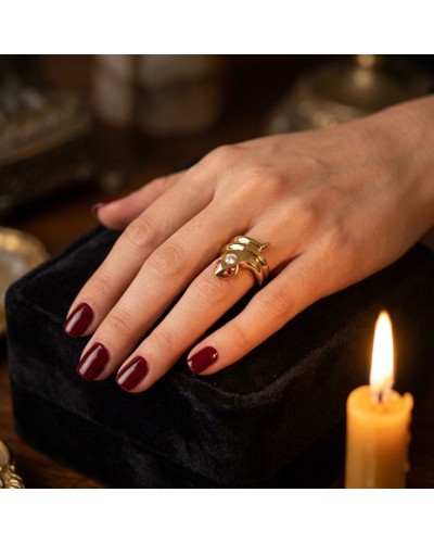 Bague KAA en or déposant sur le doigt, ambiance élégante avec bougie et boîte noire en arrière-plan