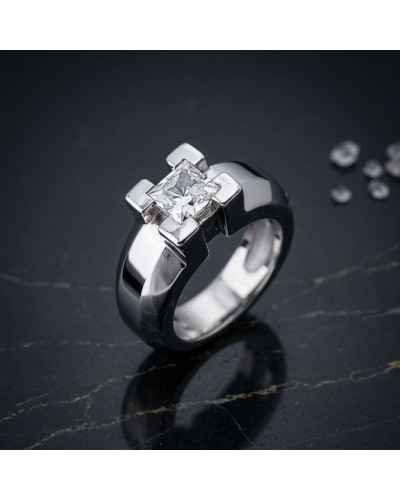 Bague JERK en métal argenté avec pierre central carrée transparente, design moderne et épuré sur une surface sombre.