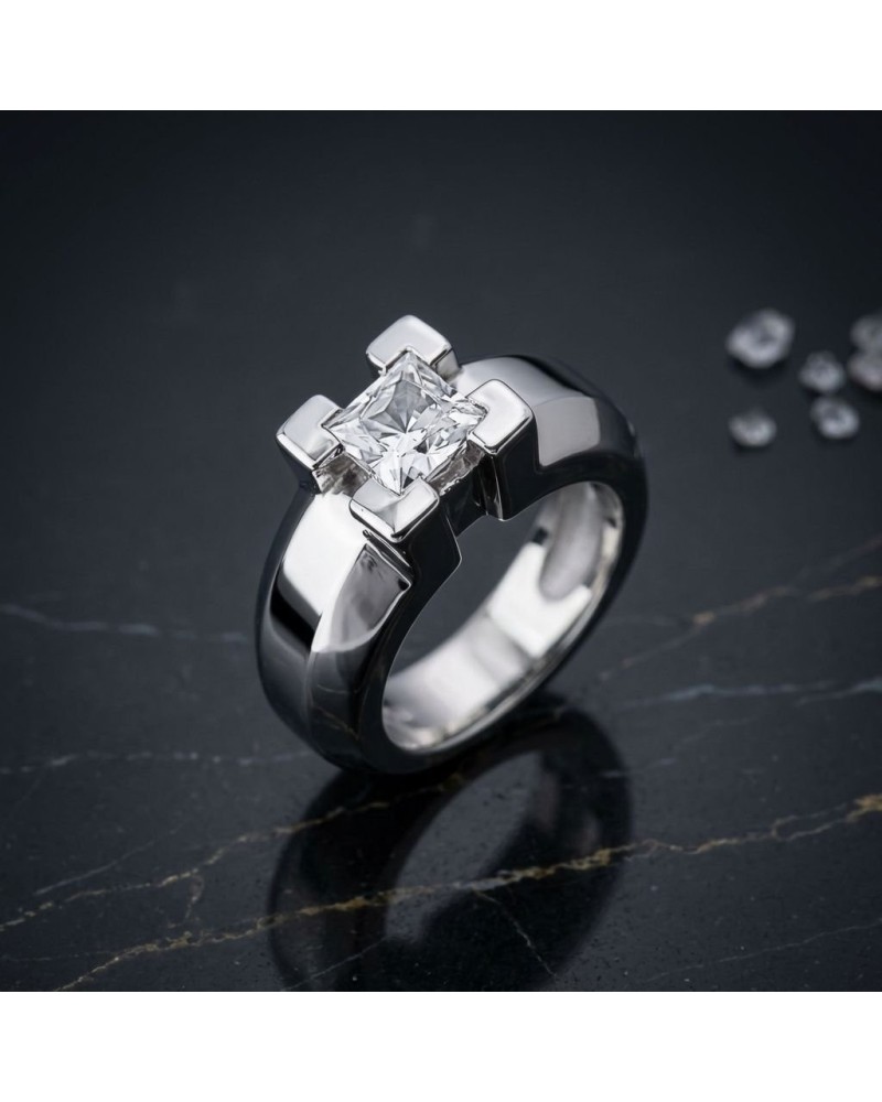 Bague JERK en métal argenté avec pierre central carrée transparente, design moderne et épuré sur une surface sombre.
