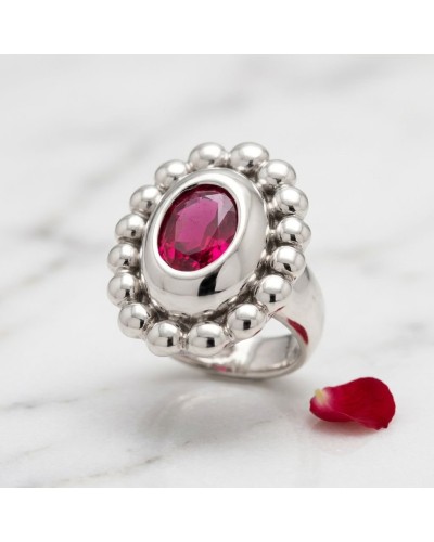Bague MARQUISE argentée avec pierre centrale rouge rubis, entourée de perles brillantes sur un marbre blanc.
