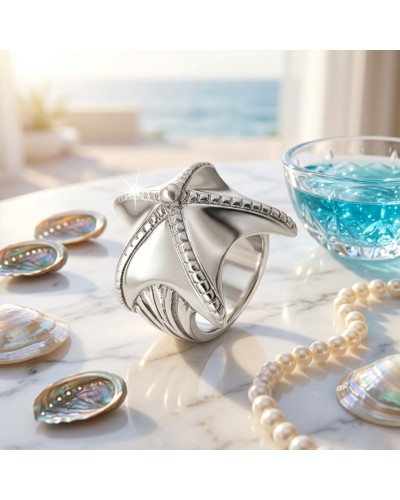 Bague ÉTOILE DE MER en argent, design mariné avec étoile marine sculptée et détails texturés, posé sur une table près de perles