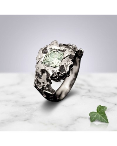 Bague LIERRE: bague argentée avec pierre centrale pale verte, motif floral sculpté autour, posé sur marbre avec une petite feuil