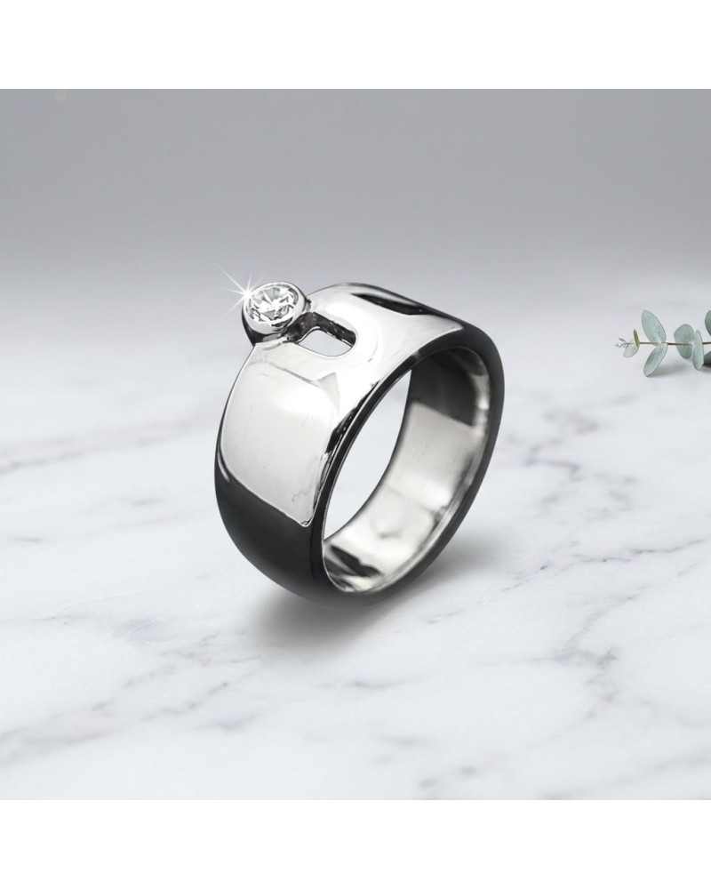Bague ZYGOTE en métal brillant avec pierre transparente, sur fond marbre clair.