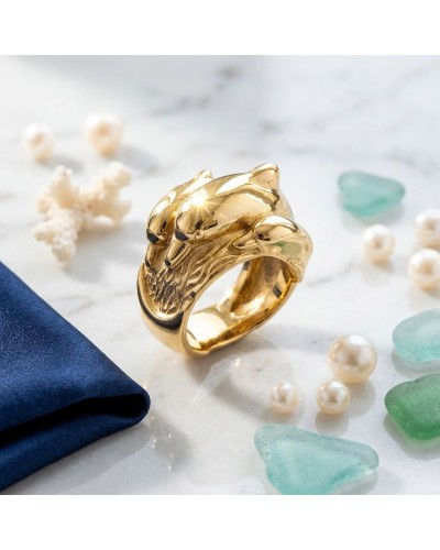 Bague dorée Grand Bleu en forme de couple de loups, portée élégante, posée sur marbre avec perles et pierres bleues.