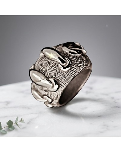 Bague noir métallique texturée avec motif en zig-zag, nommée Bague LACETS, posée sur une surface blanche.