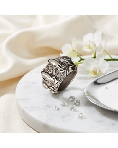 Bague LACETS en métal argenté à motif géométrique, délicatement sculptée avec des détails torsadés sur un socle marbré, accompag