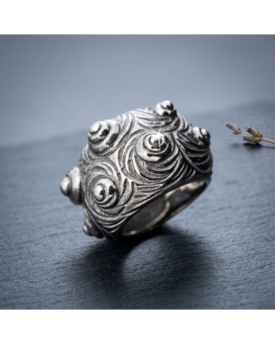 Bague MARGO en métal argenté gravée de motifs swirl circulaires, texture antique et reliefs ondulés sur fond sombre.