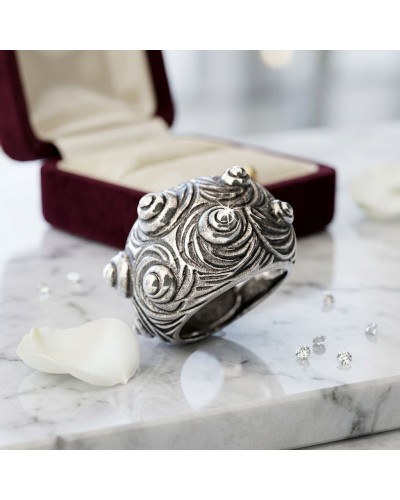 Bague MARGO argentée à motifs sculptés en spirales, présentée près d’un écrin velours rouge et de petits diamants.