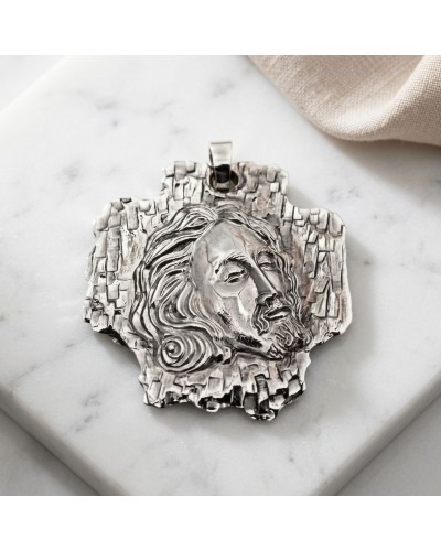 Pendentif en métal gravé d'une impression du visage de Jésus-Christ, texture rocheuse environnante, chaîne offerte.