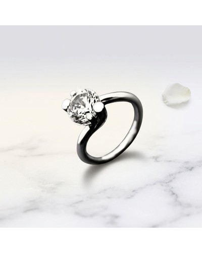 Bague HALMAHERA en métal noir avec pierre fine centrale brillante et petits demi-bouillons argentés sur une surface marbrée.
