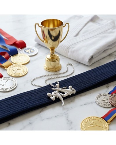 Pendentif Taekwondo argenté sur ceinture bleue, avec médaille et trophée doré en arrière-plan et médailles de compétition. Chaîn