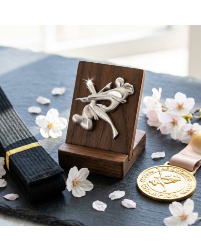Pendentif Taekwondo en métal argenté monté sur plaque en bois, près d'une ceinture noire et médaille dorée, décor fleurs pastel.