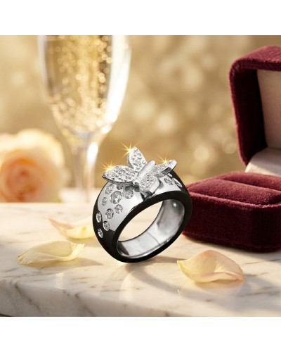 Alliance KUPU-KUPU: bague noire ornée de pierres scintillantes et d’un papillon argenté, sur un plateau de marbre avec des pétal